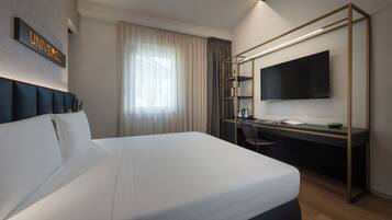 Ein modernes Hotelzimmer mit einem großen Bett, einem Schreibtisch, einem Flachbildfernseher und einem Schild mit der Aufschrift 'UNIVERSE'.