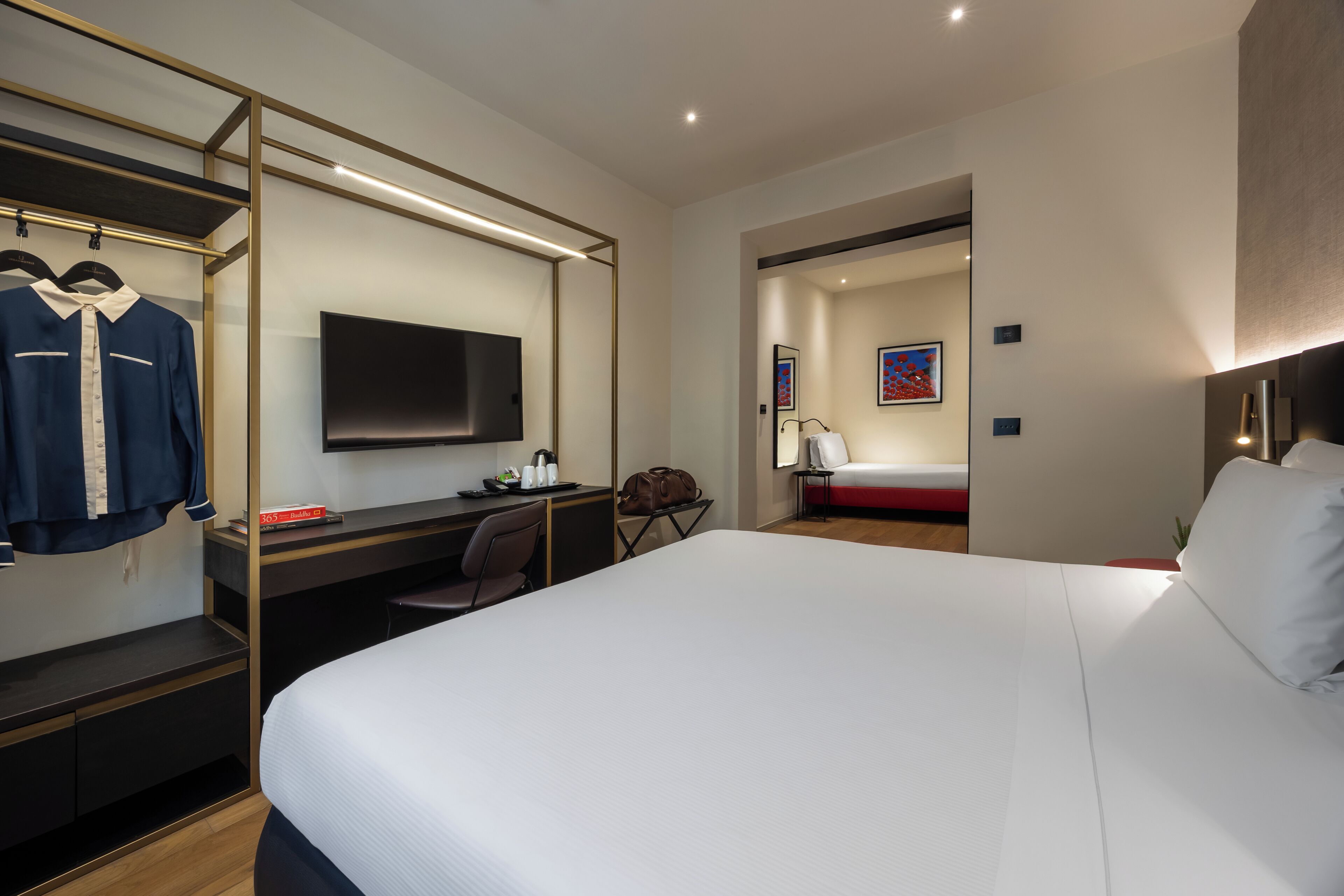 Una habitación de hotel con una cama grande, un escritorio con una silla, un televisor y un armario.