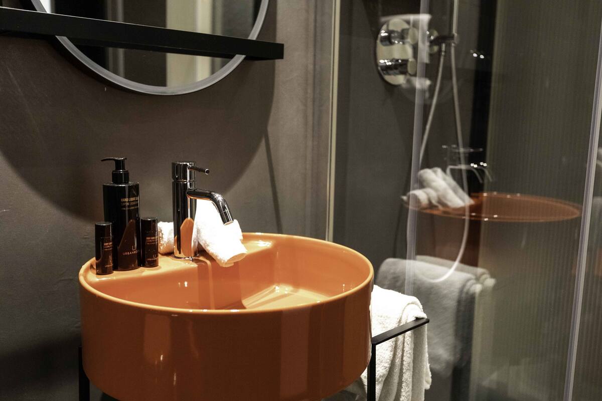 A bathroom with a round sink, a mirror, and a shower area.