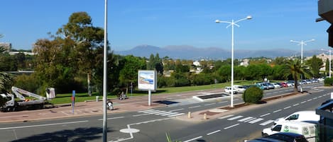 A street view with cars, a blue van, and a white truck parked on the side.
