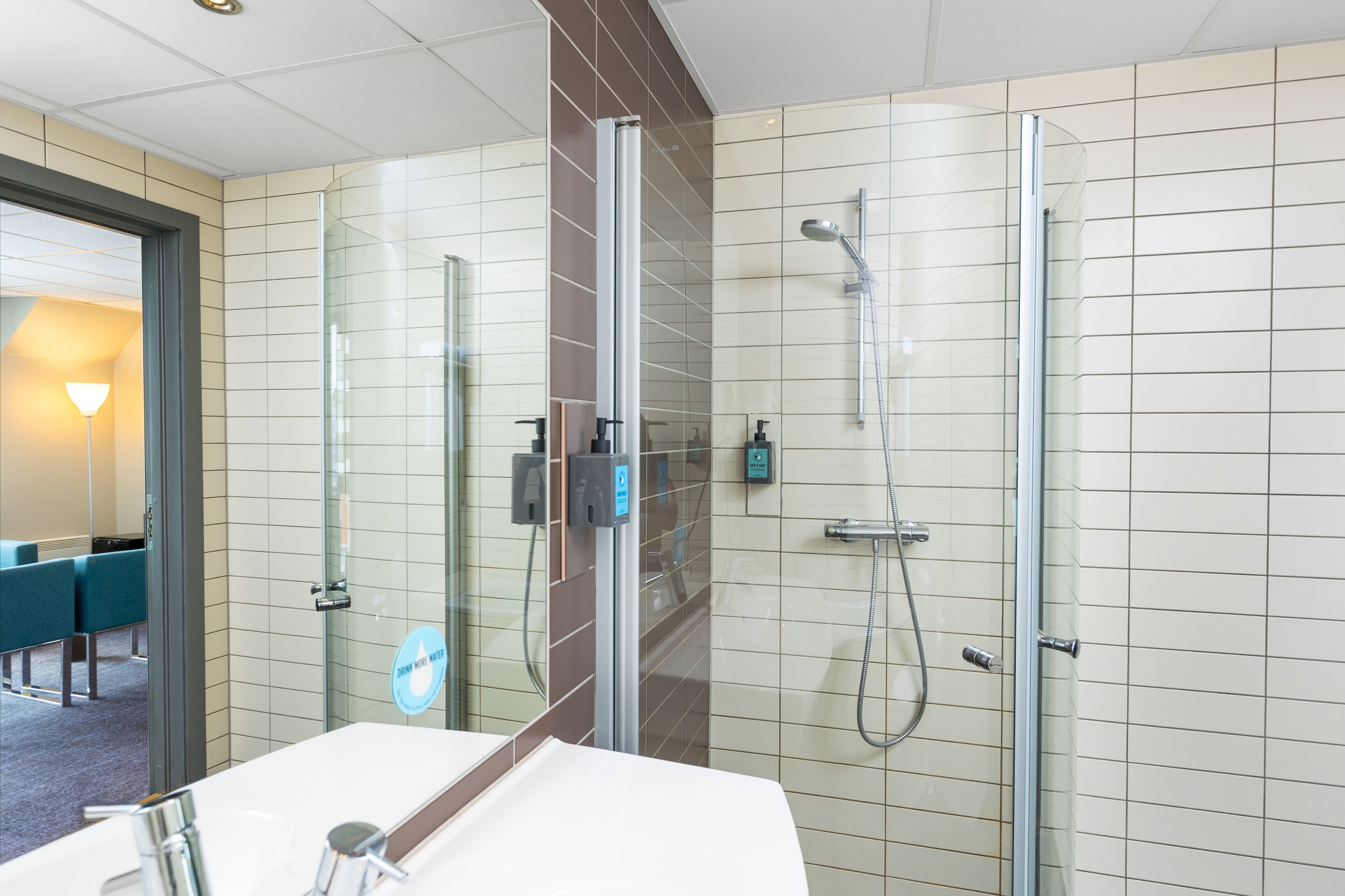 A modern bathroom with a glass shower enclosure, a sink with a mirror, and a towel rack.