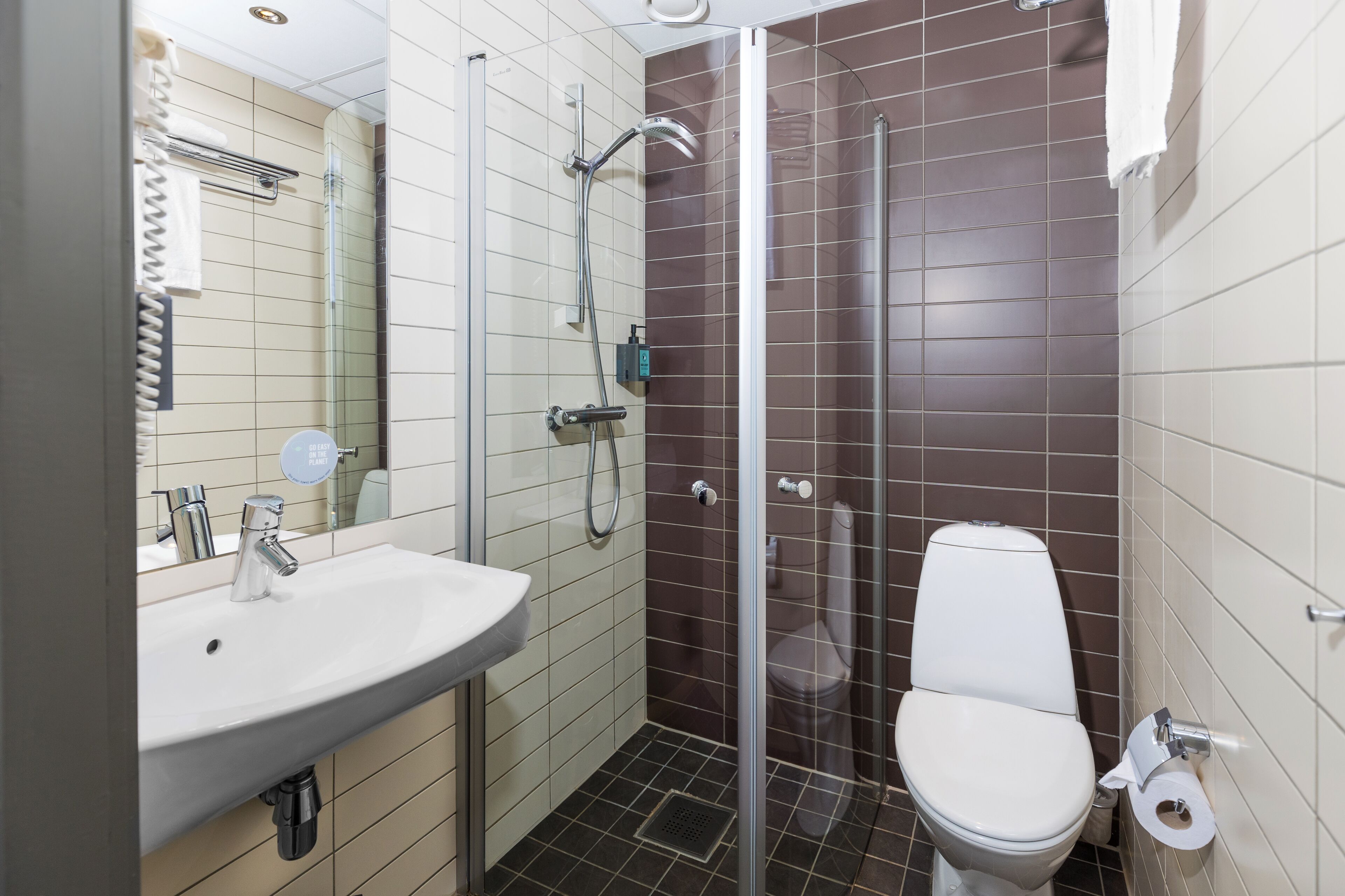 A bathroom with a white sink, a glass-enclosed shower, and a white toilet.