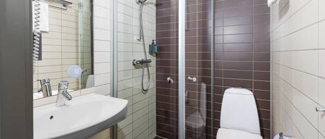 A bathroom with a white sink, a glass-enclosed shower, and a white toilet.