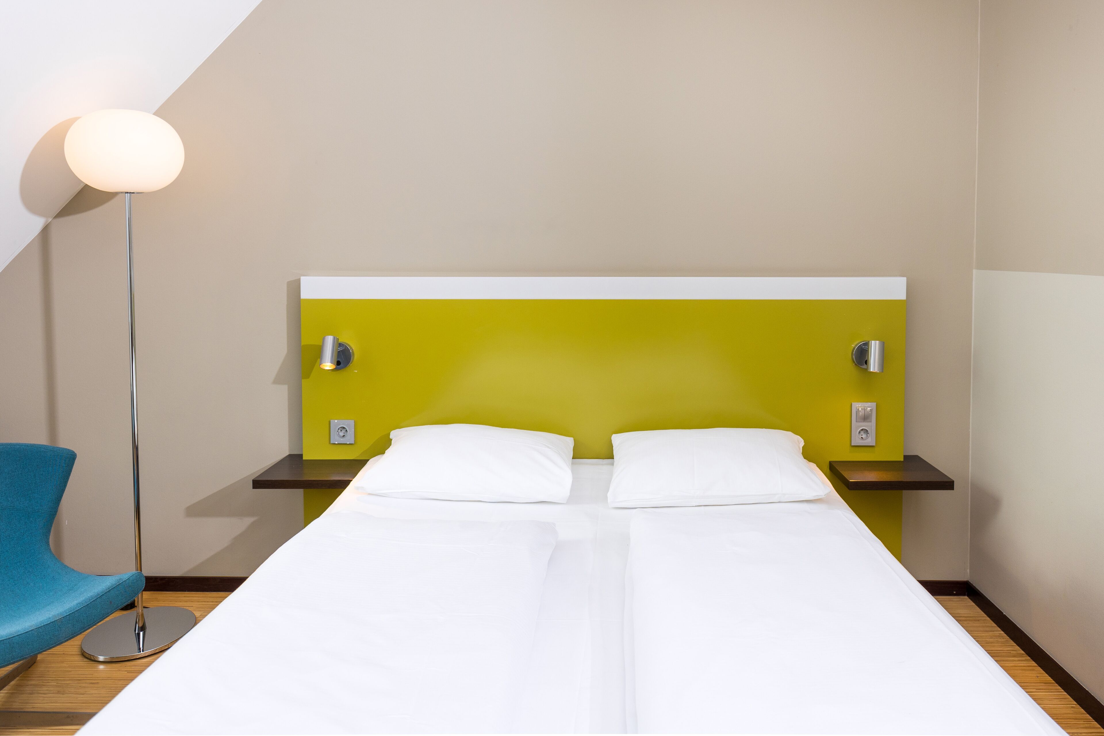 Une chambre d’hôtel avec un lit, une table de chevet, une lampe et une chaise.