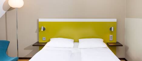 Une chambre d’hôtel avec un lit, une table de chevet, une lampe et une chaise.