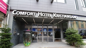 The entrance to Comfort Hotel Kristiansand with a modern facade, glass doors, and a large decorative vase at the entrance. - Comfort Hotel Kristiansand (Kristiansand)