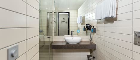 Ein modernes Badezimmer mit einem weißen Waschbecken, einem Spiegel und einem Handtuch an einem Halter.