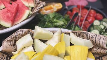 Variedad de frutas y verduras frescas exhibidas en bandejas forradas con periódico.