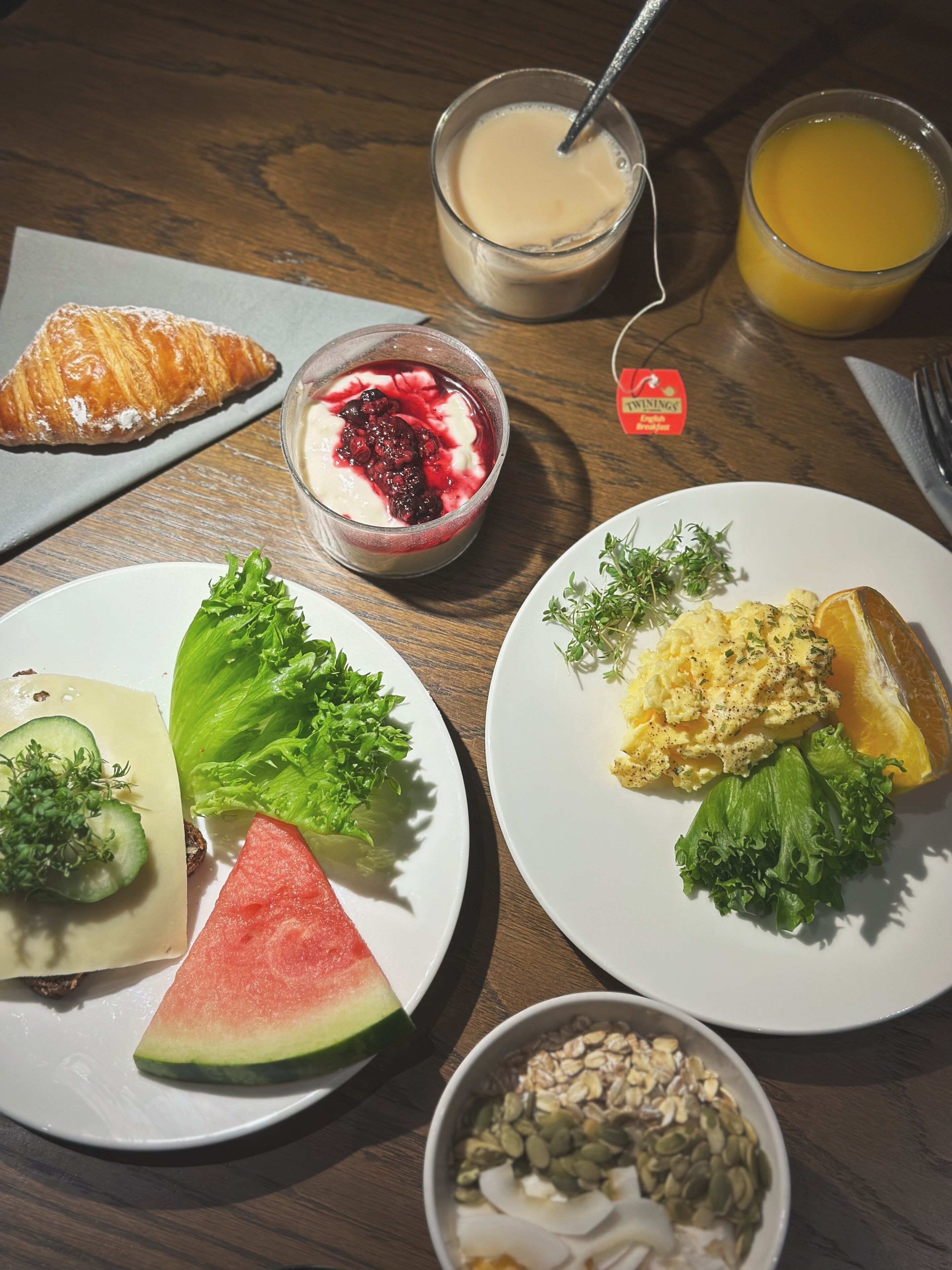 A breakfast setting with plates of food, including toast, scrambled eggs, and a fruit salad.