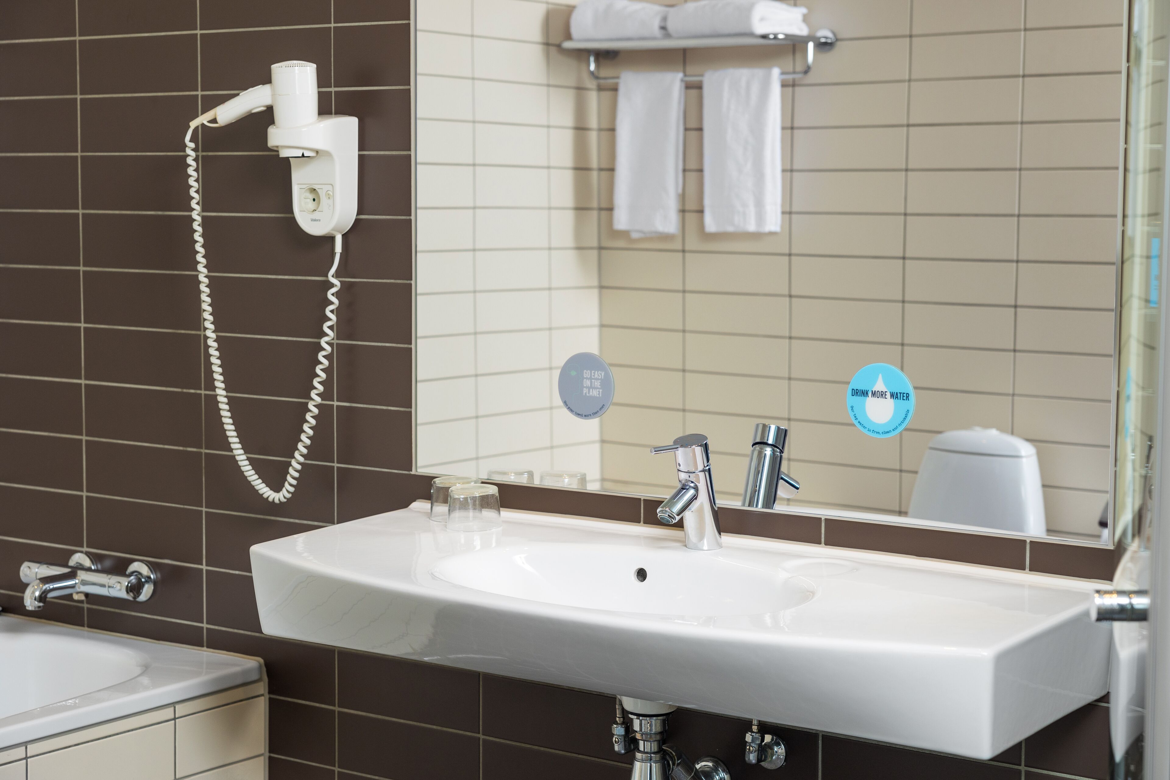 A bathroom with a white sink, a handheld hair dryer, and a towel rack.
