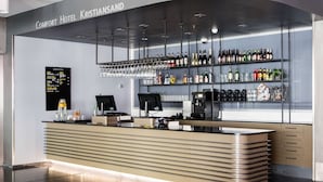 A modern hotel bar with a counter, shelves of bottles, and a menu board. - Comfort Hotel Kristiansand (Kristiansand)
