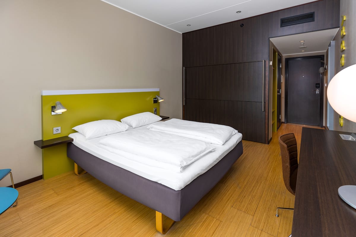Una habitación de hotel moderna con una cama grande, un escritorio y un armario.