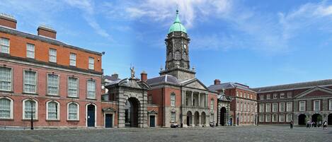 A historic building with a prominent clock tower, large windows, and a courtyard.