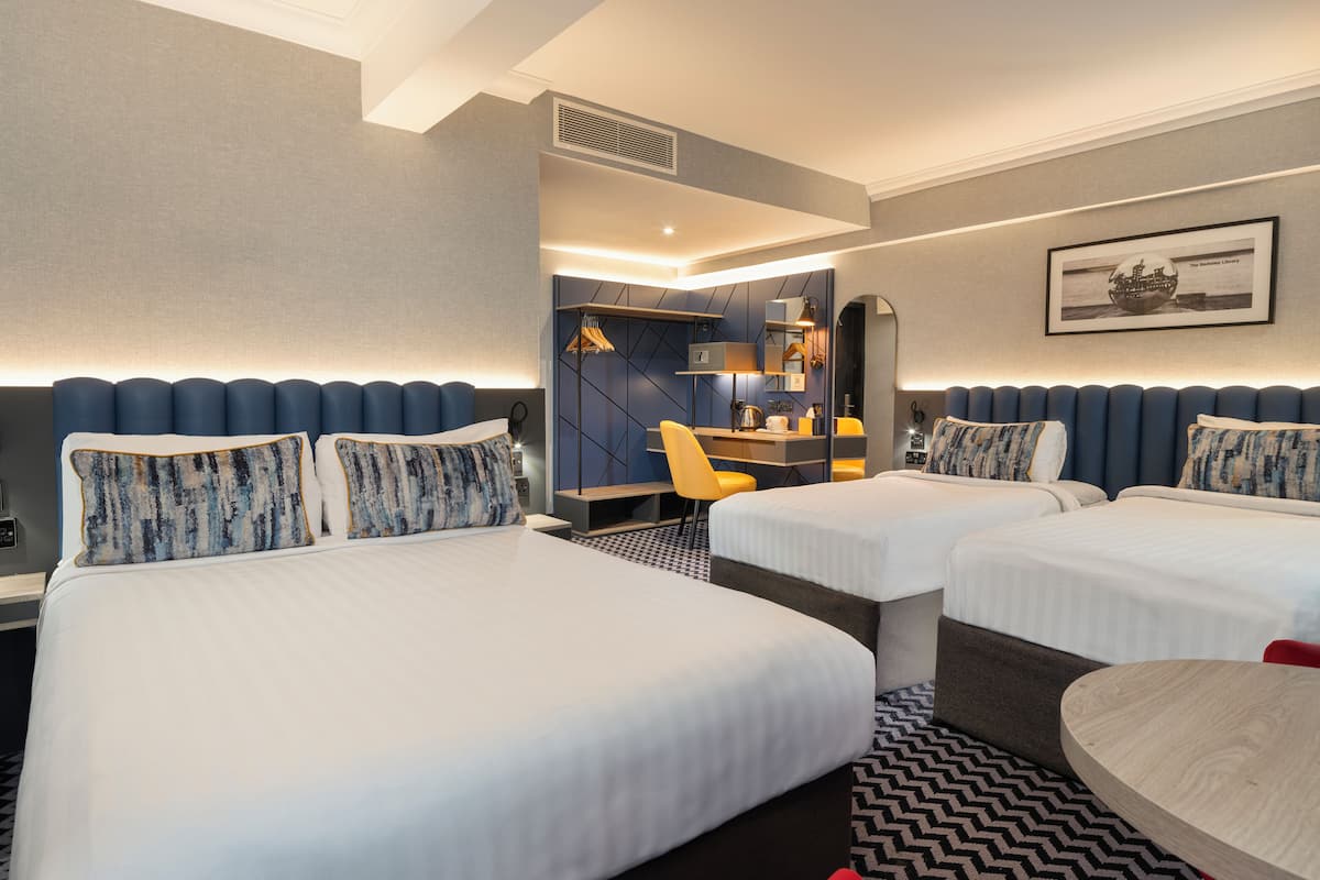 A hotel room with two beds, a desk, and a chair.
