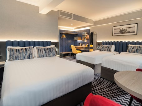 Habitación cuádruple | Ropa de cama hipoalergénica, caja fuerte, escritorio y cortinas opacas. Academy Plaza Hotel