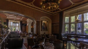 Un comedor amplio con techos altos, candelabros ornamentales y ventanas grandes que ofrecen vistas al exterior.