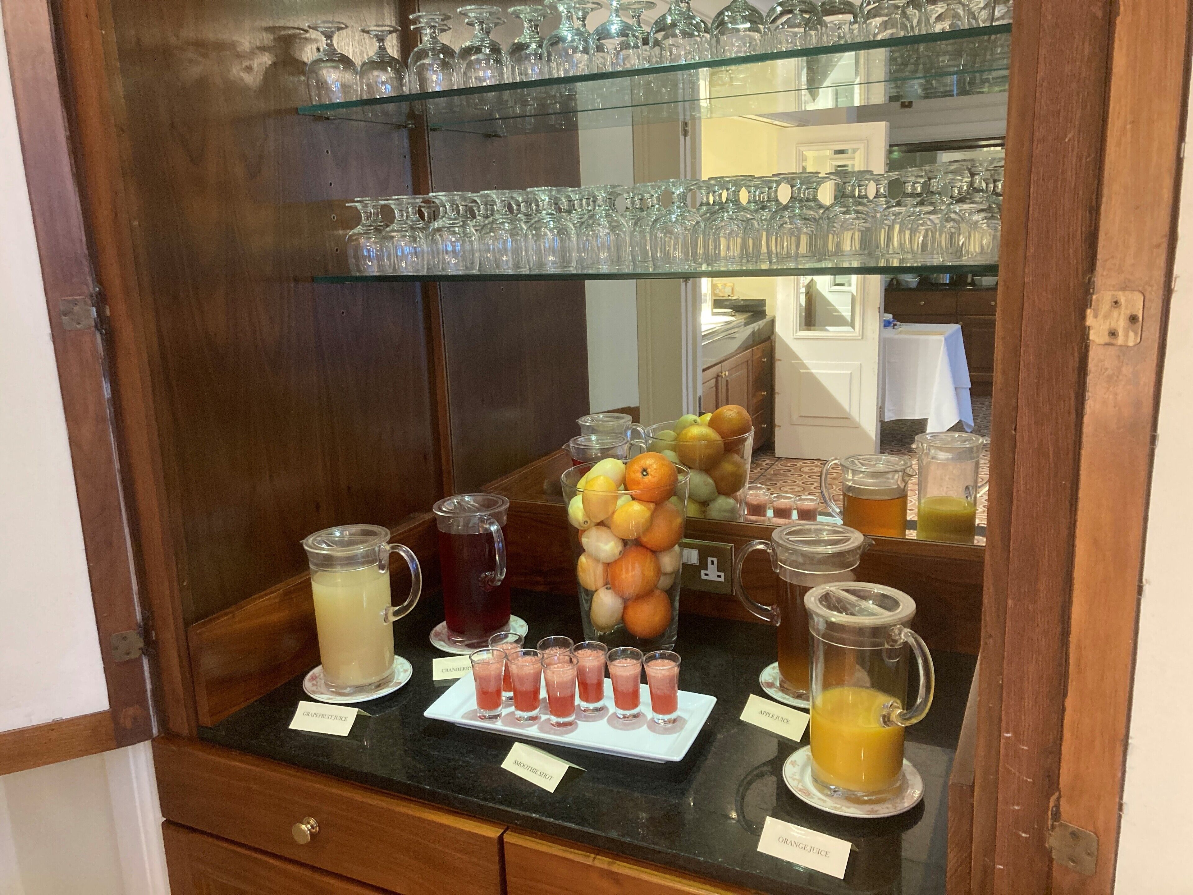 A beverage station with various drinks and a fruit display.