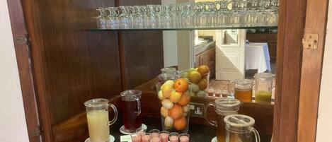 A beverage station with various drinks and a fruit display.