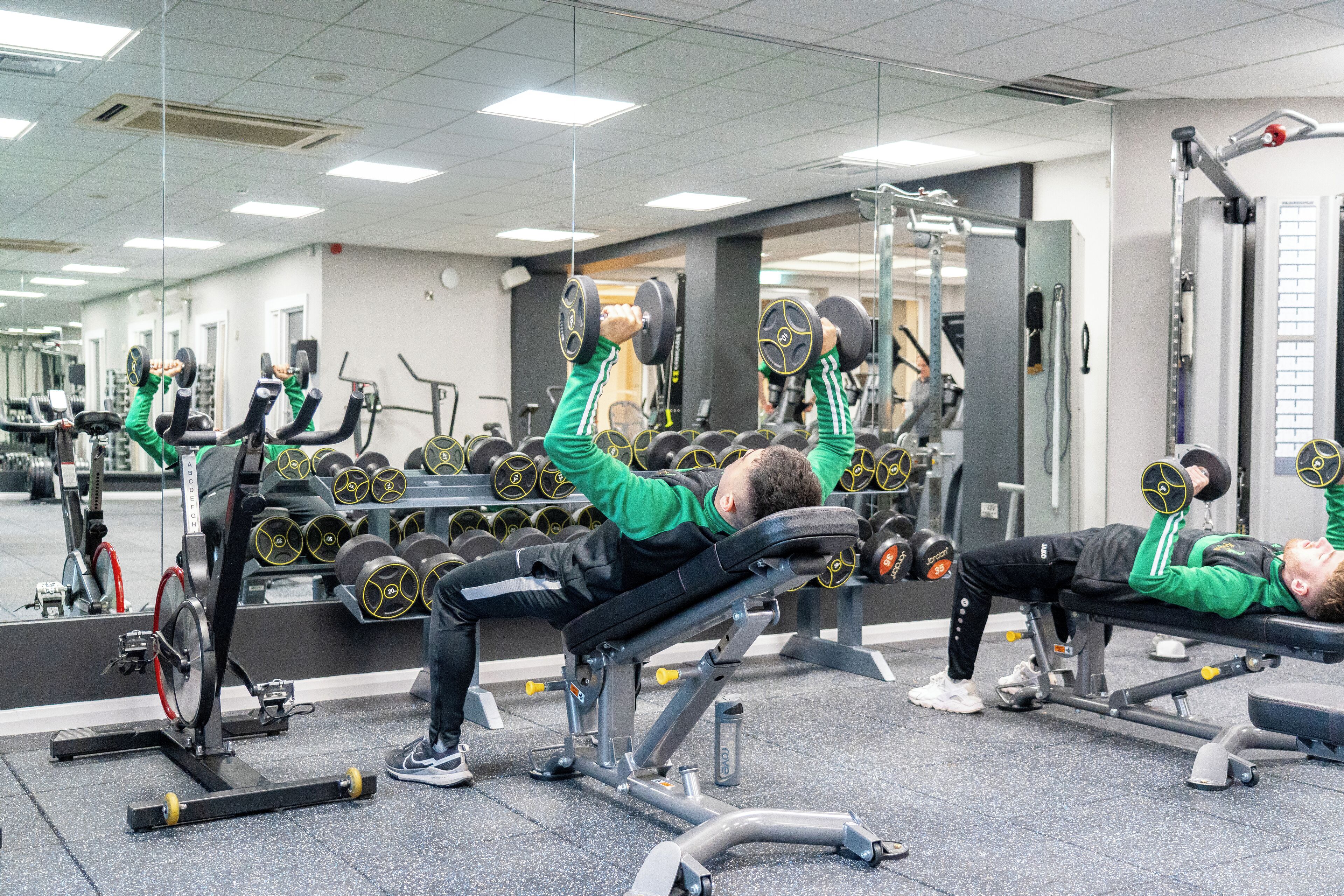 A gym with weightlifting equipment and mirrors.