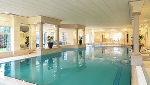 An indoor swimming pool with clear water, surrounded by columns and potted plants, with a view of the outdoors through large windows. - The Keadeen Hotel (Newbridge)