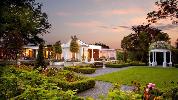 A garden with a gazebo, a white building with columns, and a well-maintained lawn. - The Keadeen Hotel (Newbridge)
