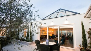 An outdoor patio with wicker furniture, a glass door leading to an interior space with seating, and a white exterior wall. - The Keadeen Hotel (Newbridge)