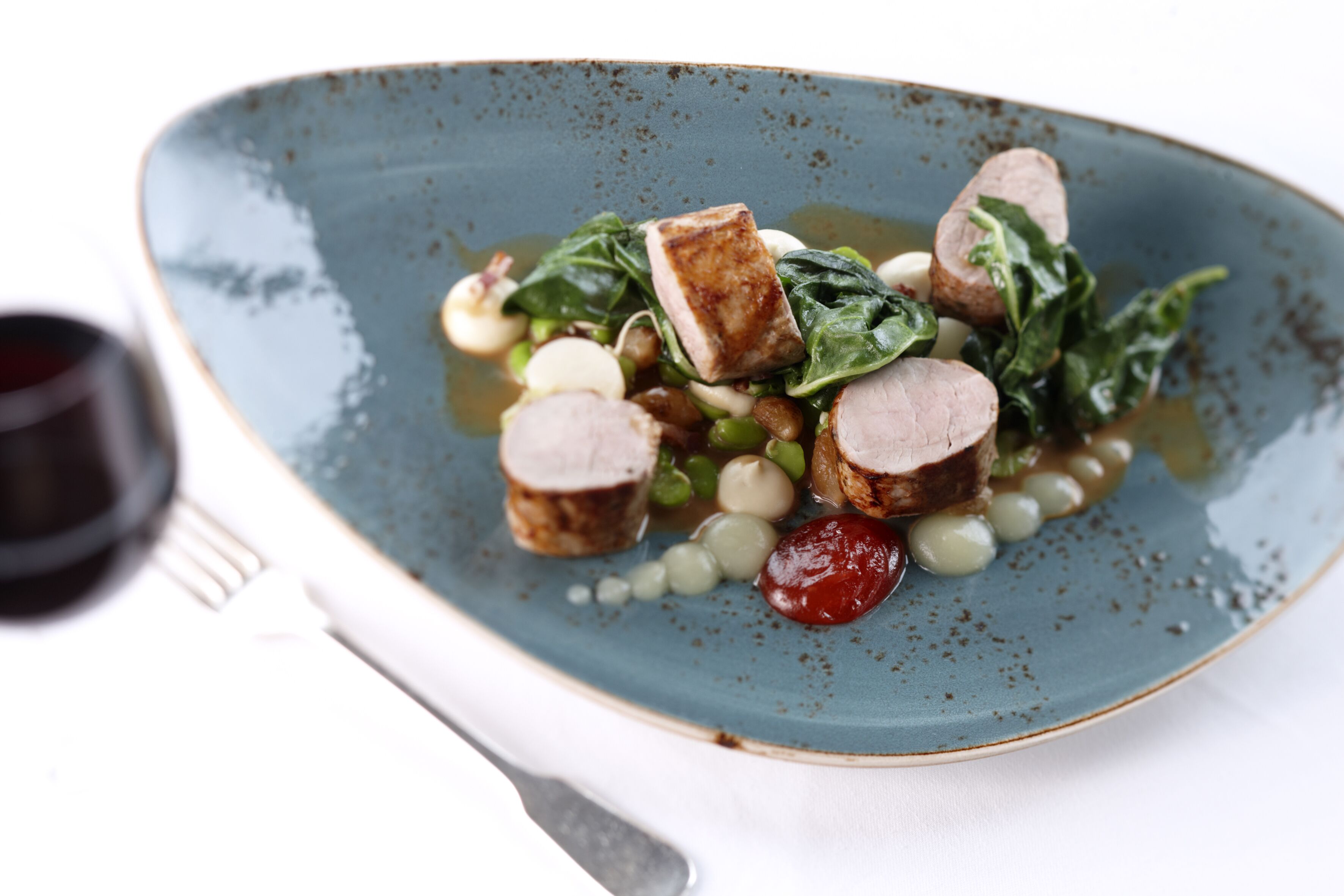 Une assiette de nourriture comprenant des tranches de viande, des légumes verts et des haricots.