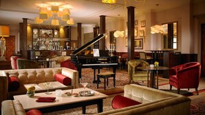 Un hall d’entrée luxueux, agrémenté d’un magnifique piano à queue, de fauteuils confortables, d’un bar et d’un éclairage élégant.