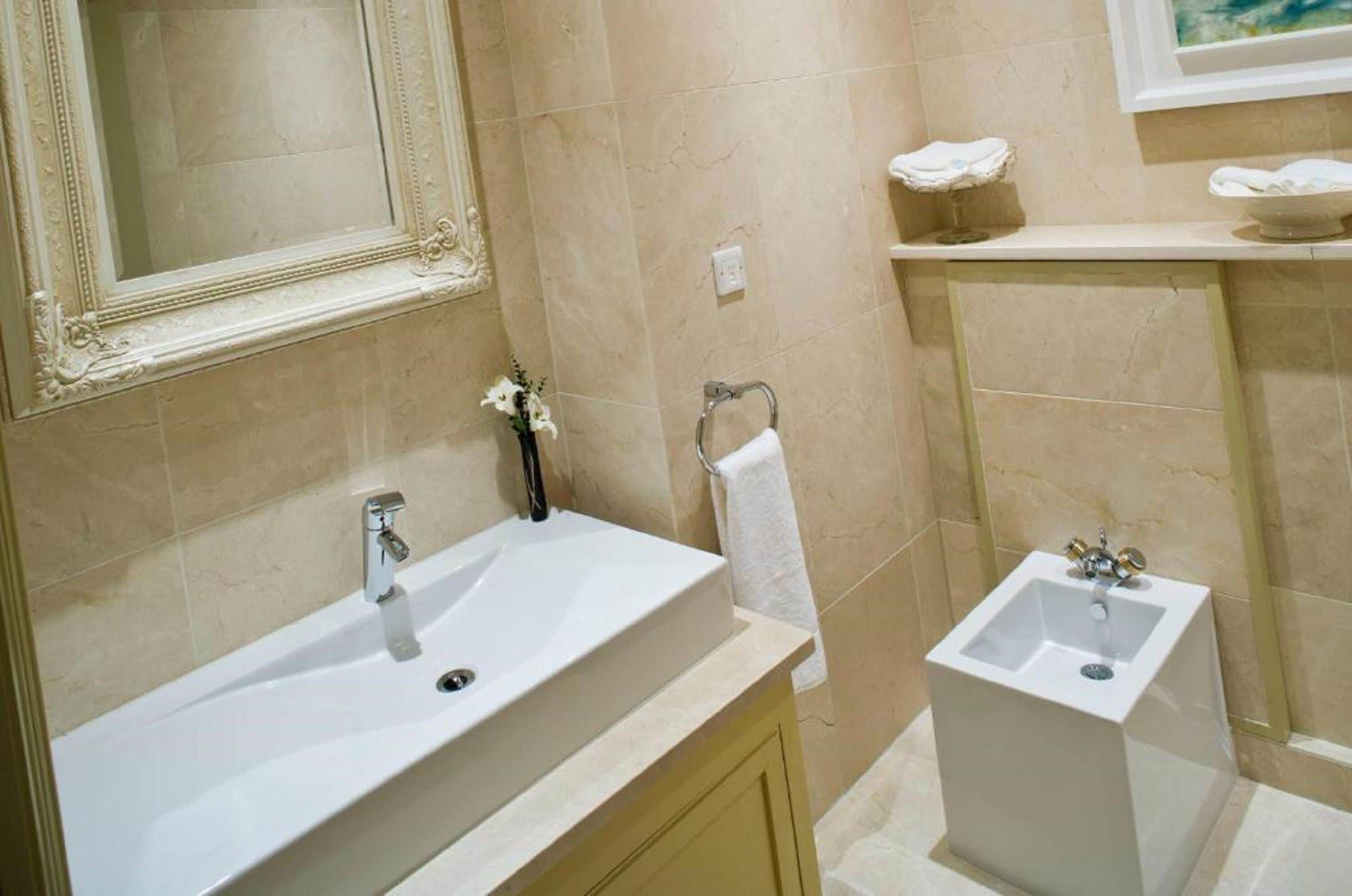 A bathroom with a large vanity sink, a smaller sink, a mirror, and a towel rack.