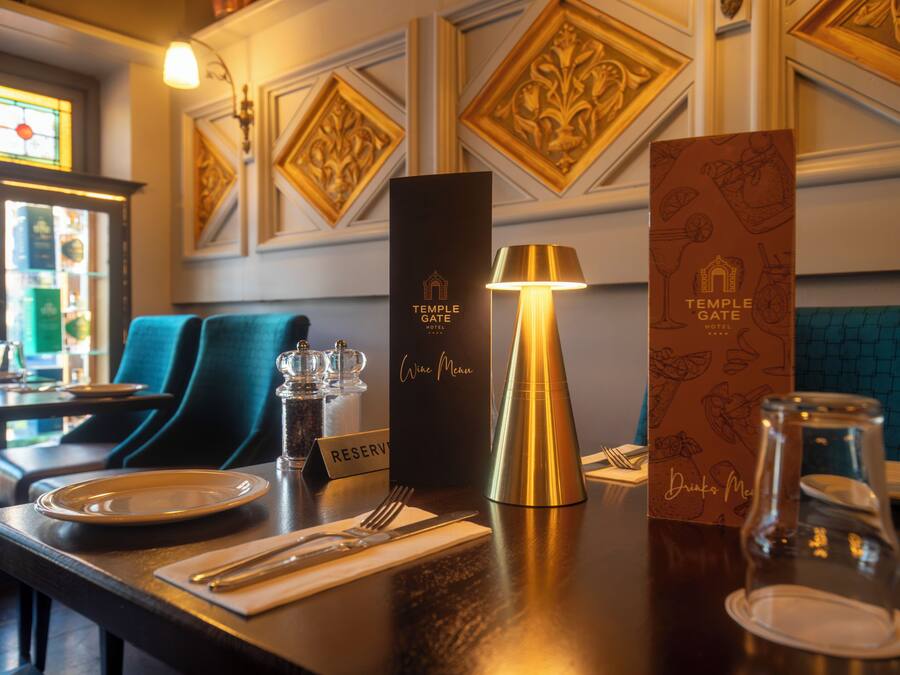 A restaurant setting with a table set for dining, a wine menu, and a reservation sign.