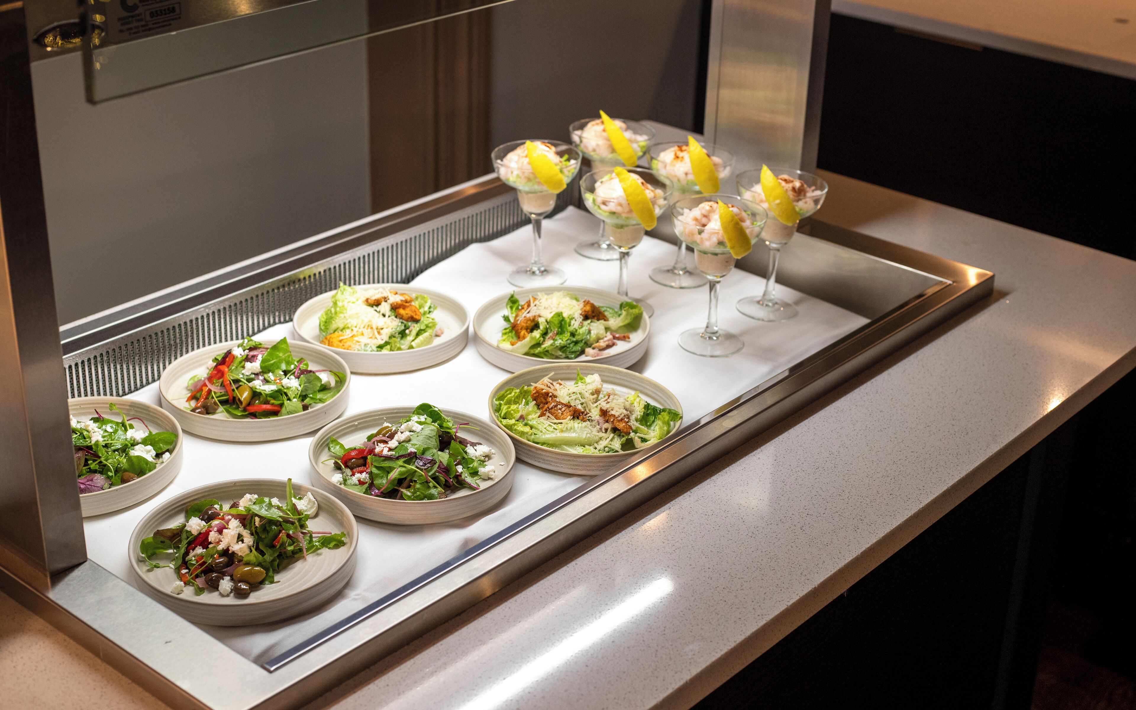 Una mesa de buffet con ensaladas y bebidas variadas.