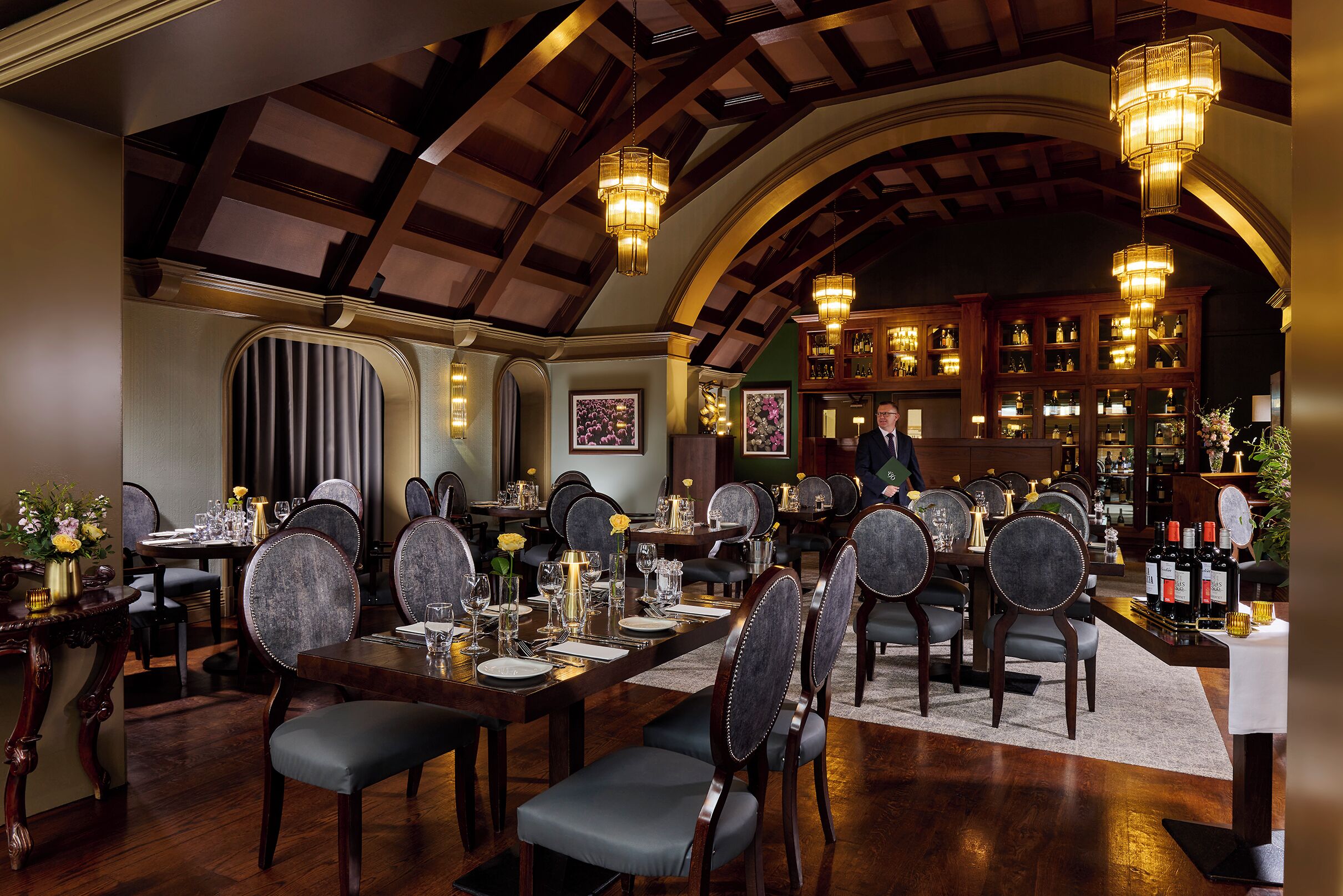 Un comedor formal con mesas de madera, sillas tapizadas y candelabros.