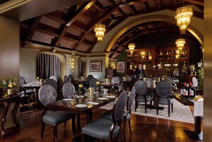 Un comedor formal con mesas de madera, sillas tapizadas y candelabros.