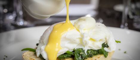 A breakfast dish with poached eggs, spinach, and hollandaise sauce on a toasted English muffin.