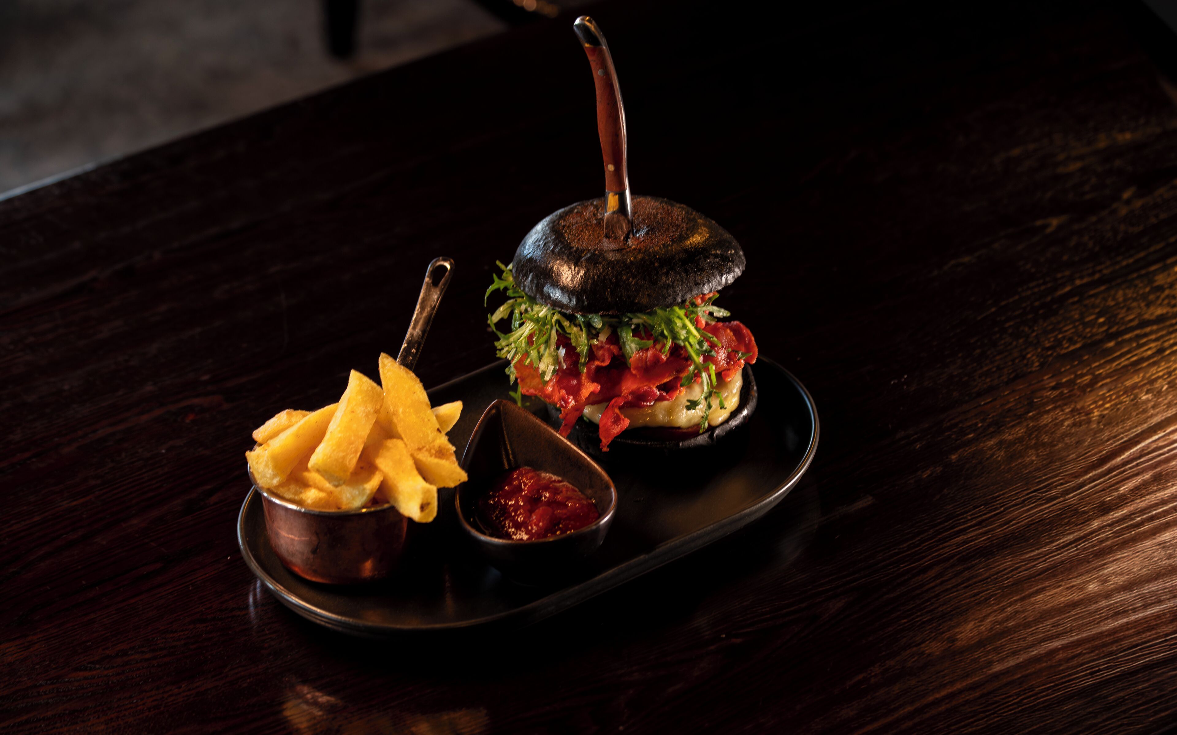 A burger with fries and sauce on a tray.