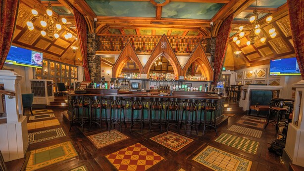 Un área de bar con techo de madera, varias barras y suelo de baldosas estampadas.