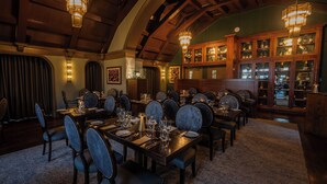 Un comedor formal con mesas de madera, sillas tapizadas y una bodega con puertas de vidrio.