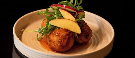 A plate with food, including meatballs and apple slices, on a white plate.