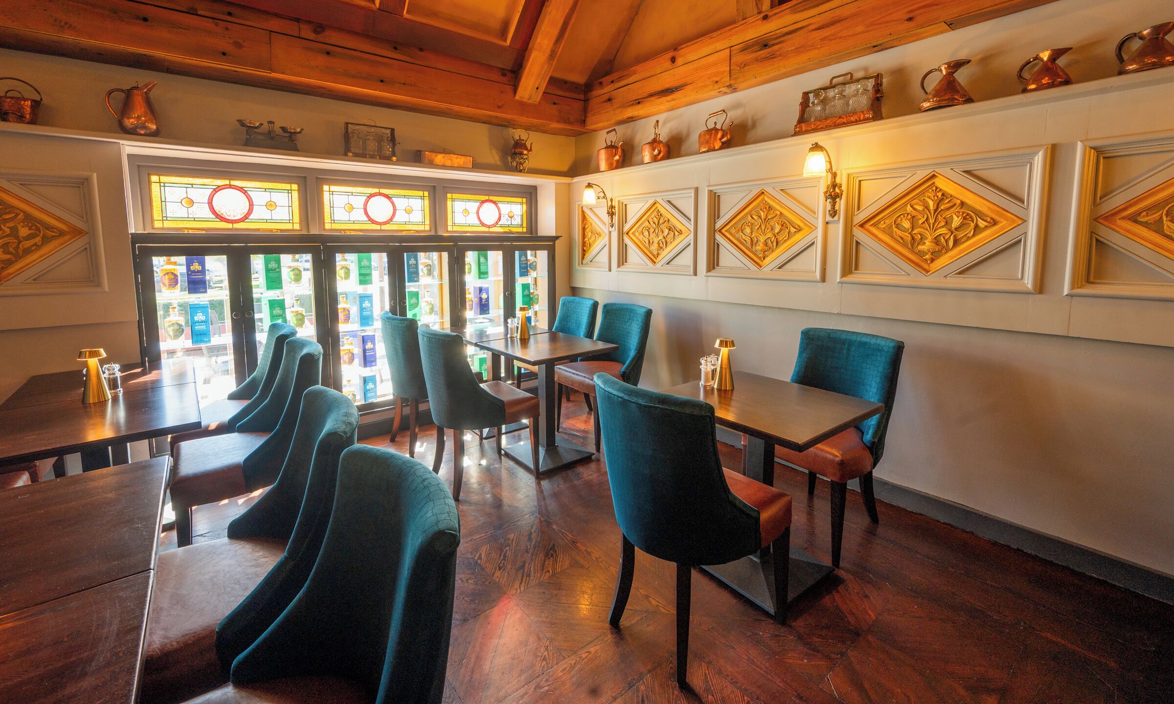 A restaurant with wooden floors, blue chairs, and a view through large windows.