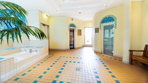 A hotel lobby with a tiled floor, a reception desk, and a bench.