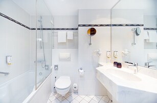 Un baño moderno con ducha envuelta en vidrio, bañera, inodoro y un mueble de tocador espacioso con espejo.