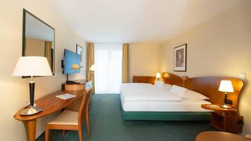 A hotel room with a bed, two bedside tables with lamps, a desk with a chair, a mirror, and a window with curtains.