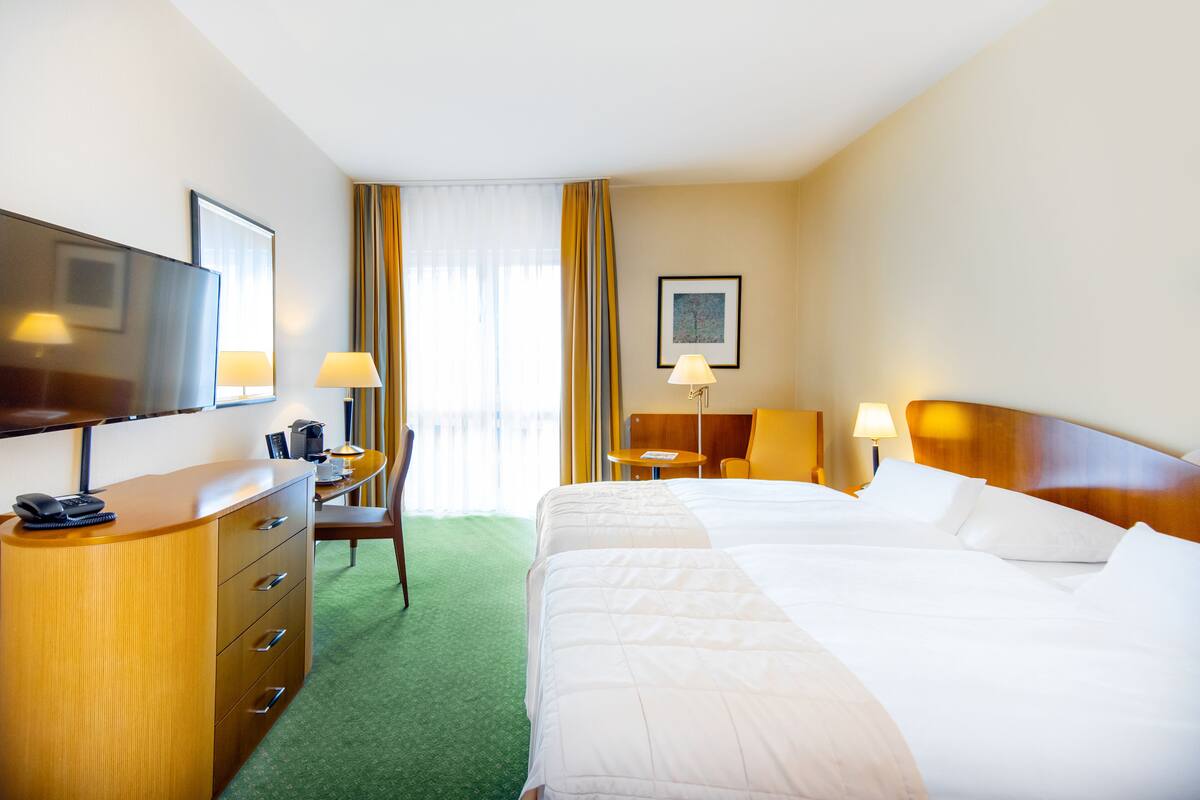 Een hotelkamer met een groot bed, een bureau met stoel, een televisie en een koffieapparaat.