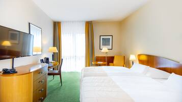A hotel room with a large bed, a desk with a chair, a television, and a coffee machine.