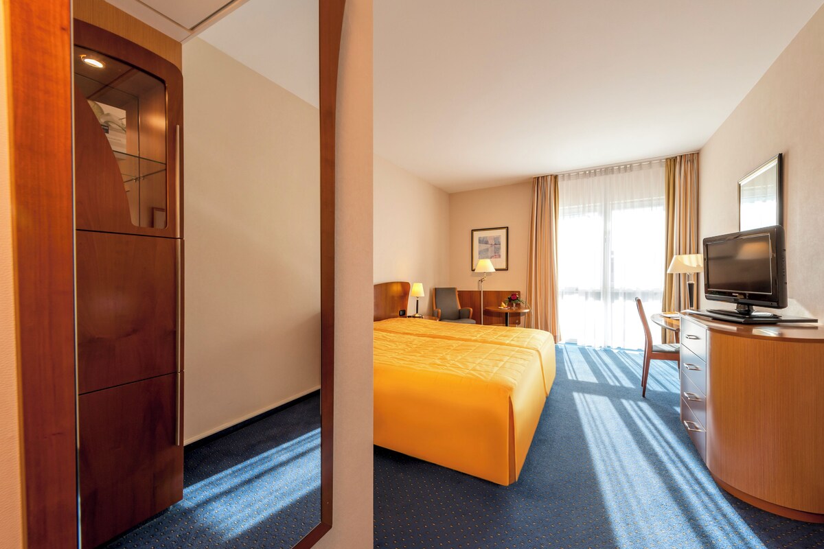 A hotel room with a bed, a desk, a television, and a mirror.