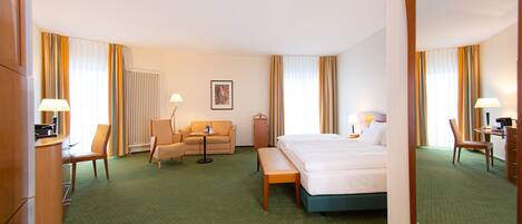 A hotel room with a bed, a desk, a chair, a sofa, and a mirror.
