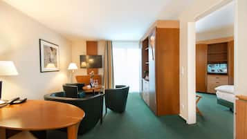 Une chambre d’hôtel comprenant un coin repas, une télévision, une armoire et un lit.