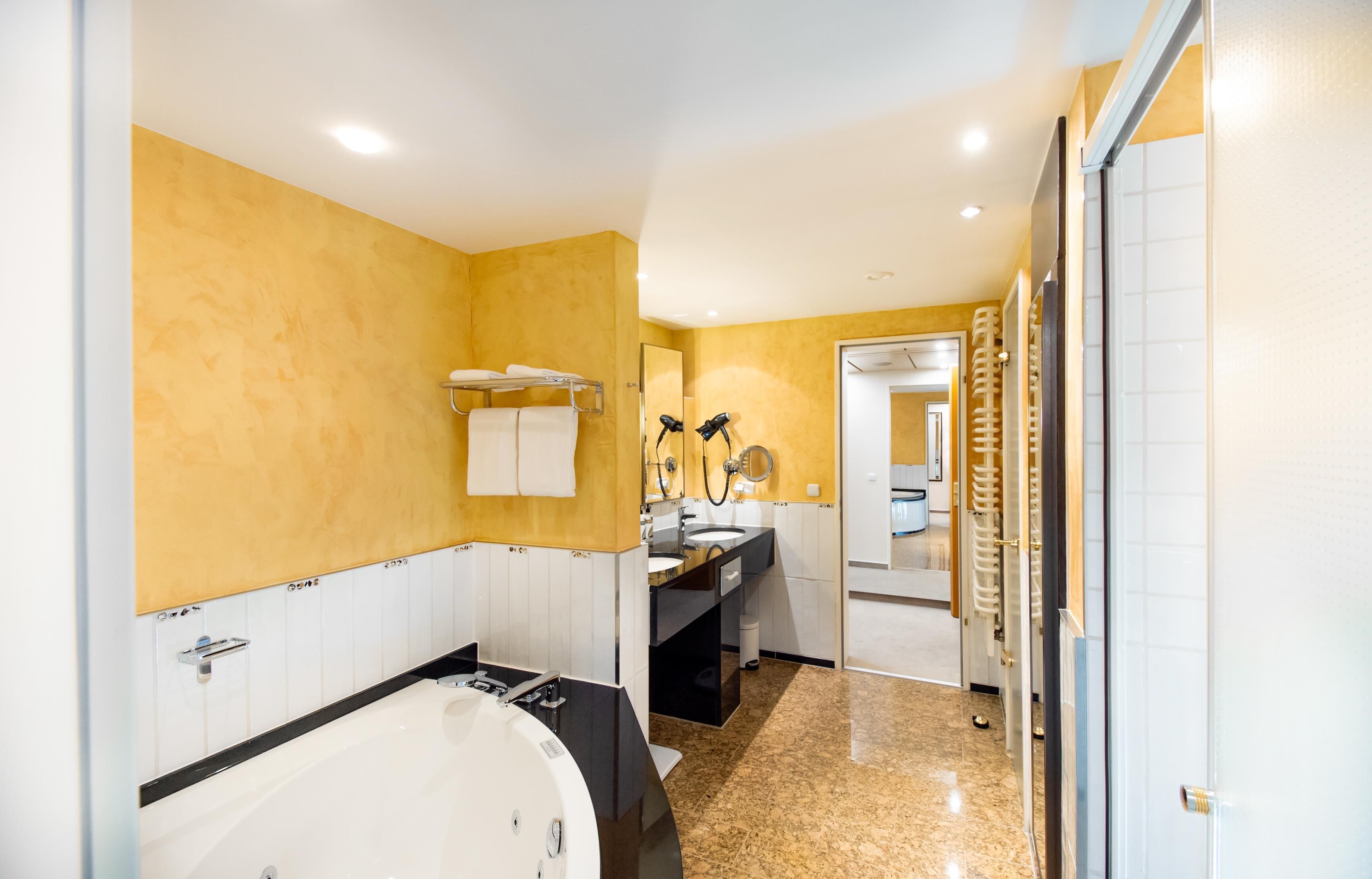 Un baño moderno con una bañera grande, un tocador con espejo y un perchero para toallas.