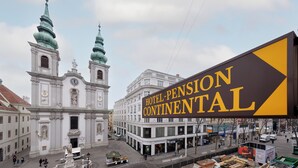 A historic building with two towers and a large sign for Hotel Pension Continental.