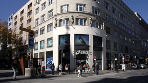 A multi-story hotel with a curved facade, large windows, and a prominent Asics shoe store entrance.